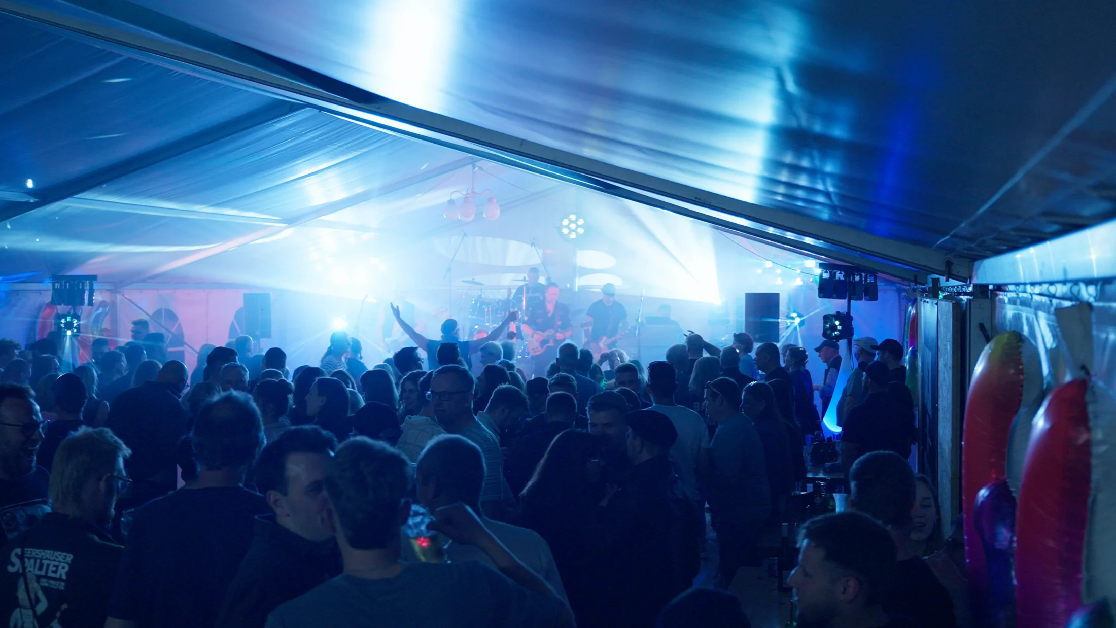 Volles Festzelt mit Publikum und blauem Bühnenlicht